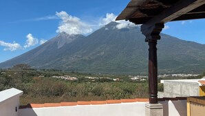 A terrace with a view of a mountain, a tiled floor, and a pergola structure.