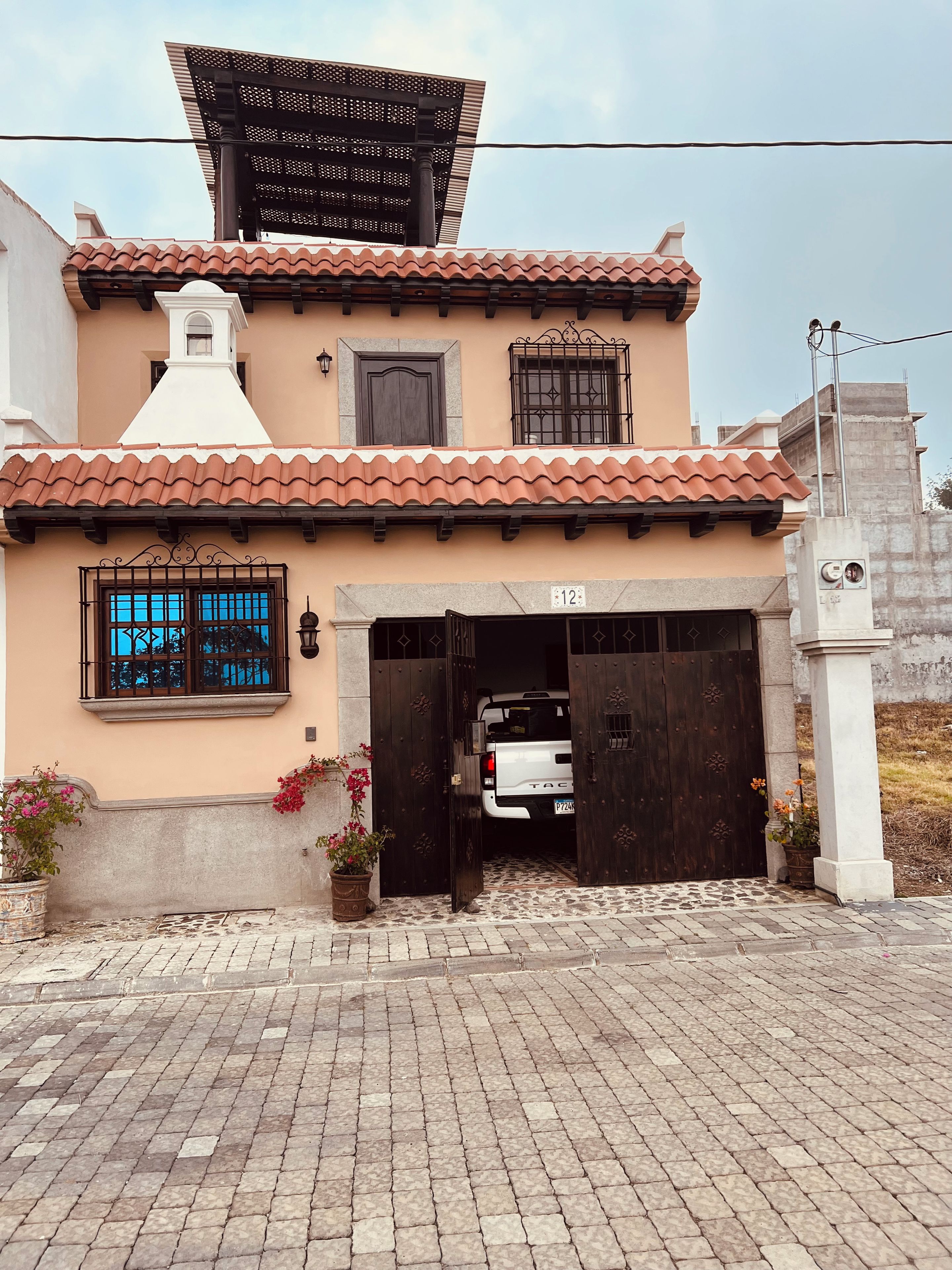 Un bâtiment avec un toit recouvert de tuiles, une porte de garage et un pot de fleurs.