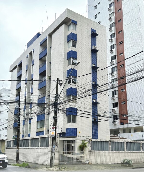 A multi-story building with balconies, a gated entrance, and visible power lines. - Apartamento Completo em Boa Viagem próximo ao Shopping Recife - Rc Hospedagens (Recife)