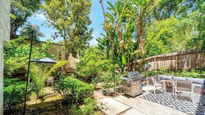 Ein Garten mit Grill, Sitzgelegenheit und üppiger Bepflanzung.