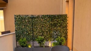 A patio with two wicker chairs and a table, a green leafy wall, and a building in the background. - Sfreg Suites Magenta - camere e B&B (Magenta)