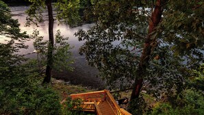 Un pont de bois qui mène à une rivière bordée d’une végétation luxuriante.