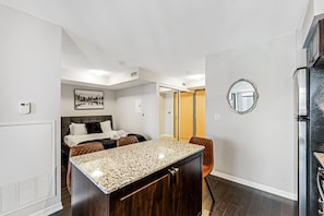 A modern hotel room with a large bed, a dining area, a kitchen, and a bathroom. - Queen Verity Suites (Toronto)