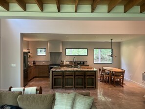 Cozinha moderna com ilha central, armários de madeira e área de refeições com cadeiras.
