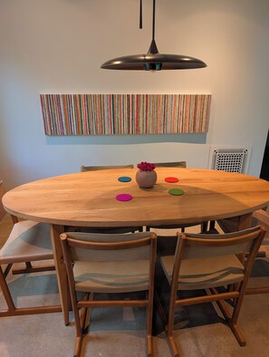 Uma mesa de jantar redonda de madeira com uma luminária pendente moderna, rodeada por cadeiras de madeira com assentos acolchoados.