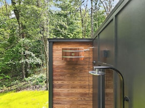 A wooden exterior wall with a metal door, a window, and a metal faucet. - Woodhaven Luxury Forest Retreat w/ Sauna & River Access (Bentonville)