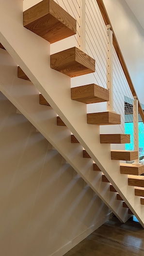 A modern staircase with wooden steps and white railings. - Woodhaven Luxury Forest Retreat w/ Sauna & River Access (Bentonville)