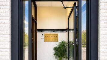 Une entrée moderne avec des portes vitrées, une plante en pot et un sol carrelé.