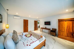 A bedroom with a bed, a TV, a wardrobe, and a desk. - Villa Lotus Seminyak (Badung)