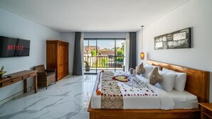 Een slaapkamer met een bed, een televisie, een houten kledingkast, een bureau en uitzicht op het exterieur.