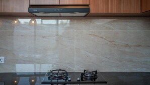 Een keuken met een gasfornuis, een afzuigkap en houten keukenkastjes.