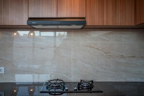 A kitchen with a gas stove, a range hood, and wooden cabinets. - Villa Lotus Seminyak (Badung)