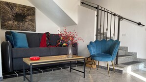 A modern living room with a sofa, a blue armchair, a coffee table, and a staircase. - CASA SARDAIGNE—3 bedrooms, 6 beds—house with a separate studio and a garden. (Sarroch)