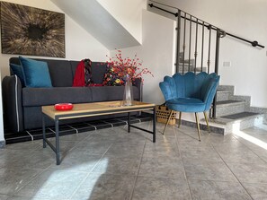 Ein modernes Wohnzimmer mit einer Couch, einem blauen Sessel, einem Couchtisch und einer Treppe.