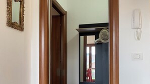 A hallway with a wooden door frame, a mirror, a telephone, and a cabinet with a mirror above it. - CASA SARDAIGNE—3 bedrooms, 6 beds—house with a separate studio and a garden. (Sarroch)