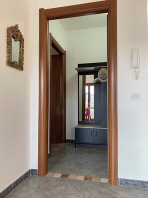 Ein Flur mit Holztürrahmen, einem Spiegel, einem Telefon und einem Schrank mit Spiegel darüber.
