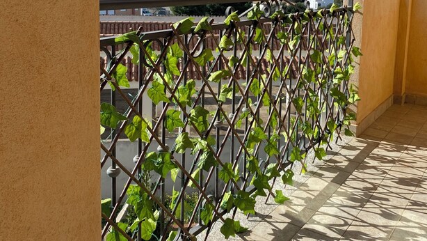 A balcony with a view of mountains, a tiled floor, and a metal railing with green plants. - CASA SARDAIGNE—3 bedrooms, 6 beds—house with a separate studio and a garden. (Sarroch)