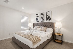 Ein Schlafzimmer mit einem großen Bett, zwei Nachttischlampen und drei abstrakten Wandbildern.