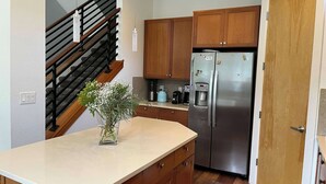 A kitchen with wooden cabinets, a stainless steel refrigerator, a coffee maker, and a vase with flowers on the counter. - Beautiful pet-friendly, 4-bedroom, 3.5 bath house in North Boulder (Boulder)