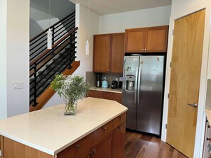A kitchen with wooden cabinets, a stainless steel refrigerator, a coffee maker, and a vase with flowers on the counter. - Beautiful pet-friendly, 4-bedroom, 3.5 bath house in North Boulder (Boulder)