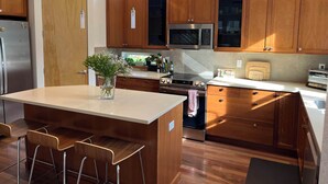 A modern kitchen with wooden cabinets, a central island with bar stools, a built-in oven, and a microwave. - Beautiful pet-friendly, 4-bedroom, 3.5 bath house in North Boulder (Boulder)