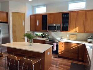A modern kitchen with wooden cabinets, a central island with bar stools, a built-in oven, and a microwave. - Beautiful pet-friendly, 4-bedroom, 3.5 bath house in North Boulder (Boulder)