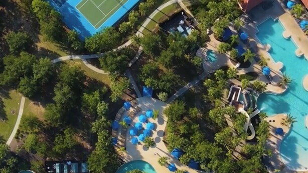 Ein Luftbild eines Resorts mit Schwimmbad, Wasserrutsche und Tennisplatz.
