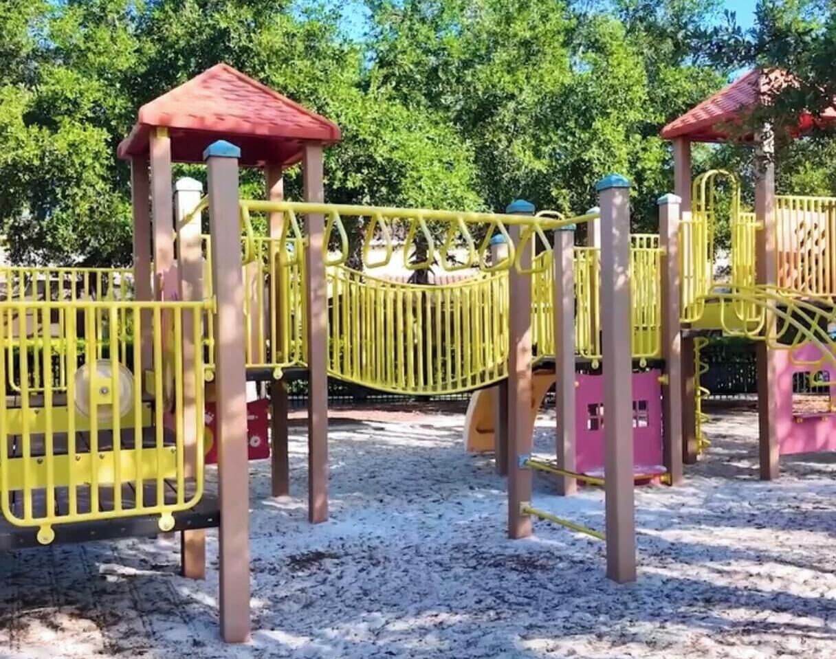 A playground with yellow and pink play structures, including a swing set and climbing elements.