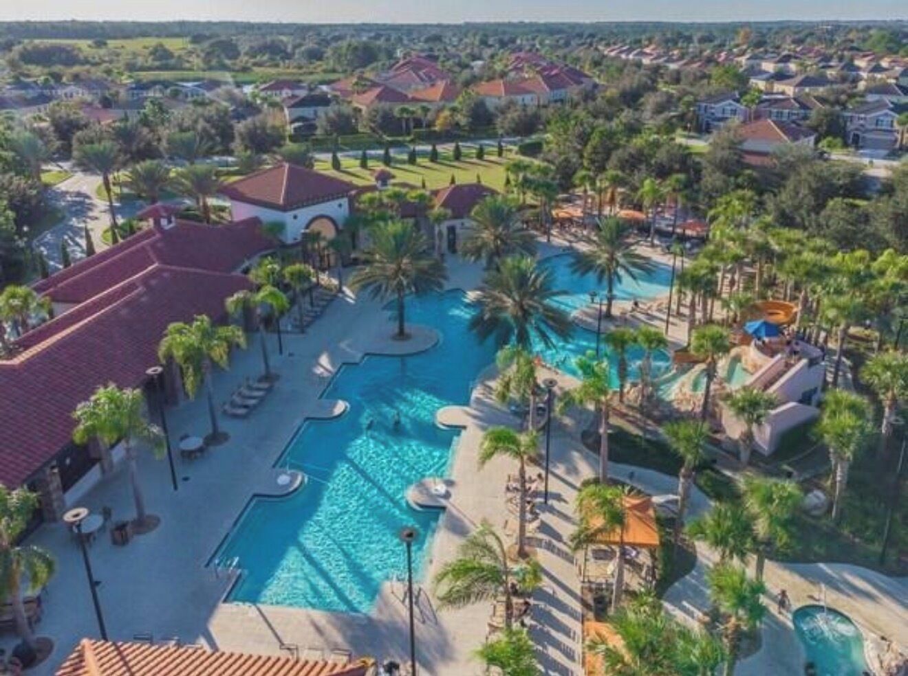 A resort with a large swimming pool, palm trees, and multiple buildings.