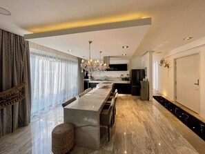 A modern kitchen with a marble island, stainless steel appliances, and a chandelier. - Black House - Stylish 3BR in Aldea Zama with Rooftop (Tulum)