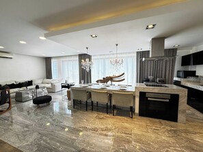 Una sala de estar moderna con comedor, cocina y un gran ventanal con cortinas.