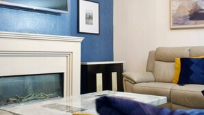 A living room with a fireplace, a sofa, a coffee table, and a painting on the wall.
