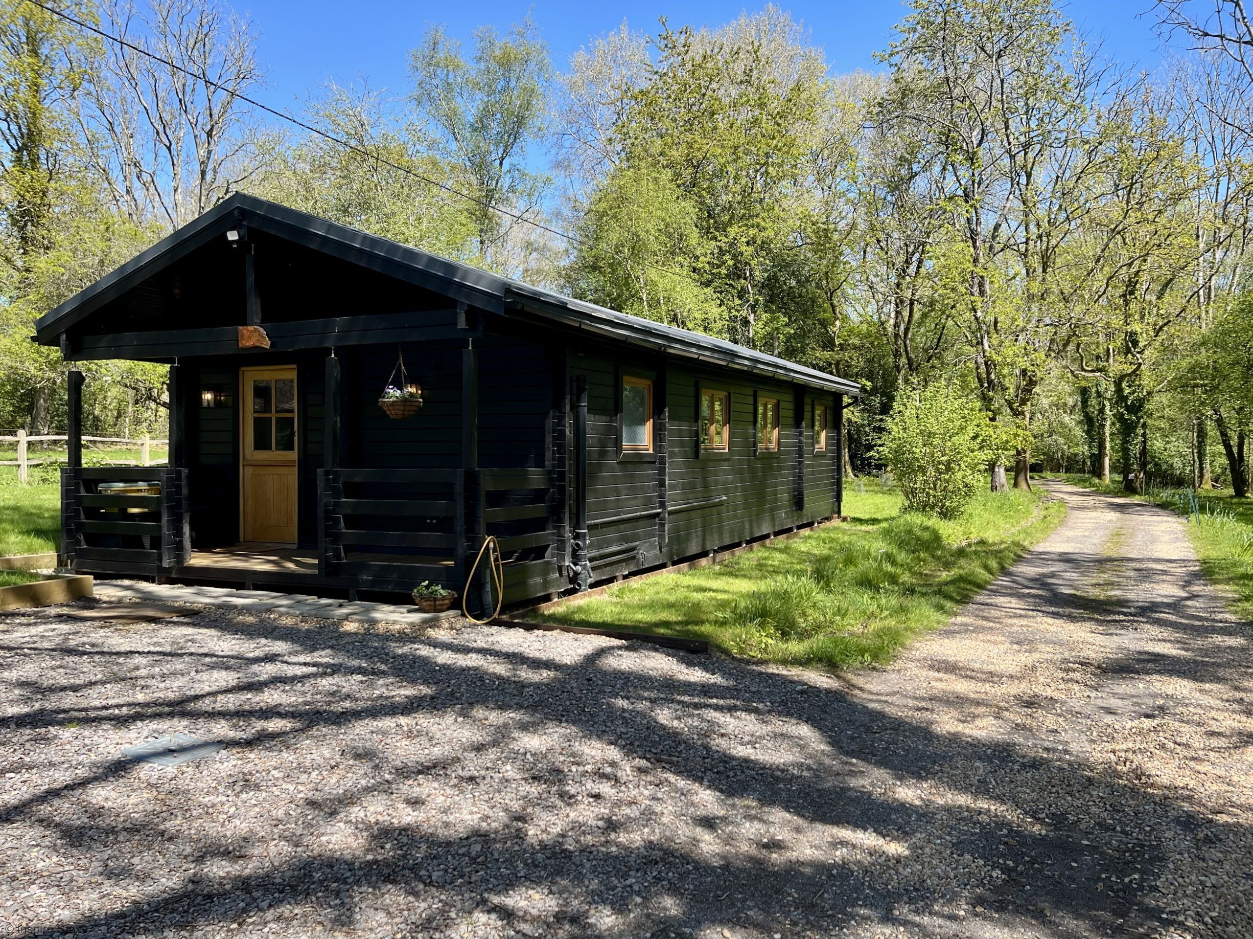 A wooden cabin with a porch, a door, and windows.