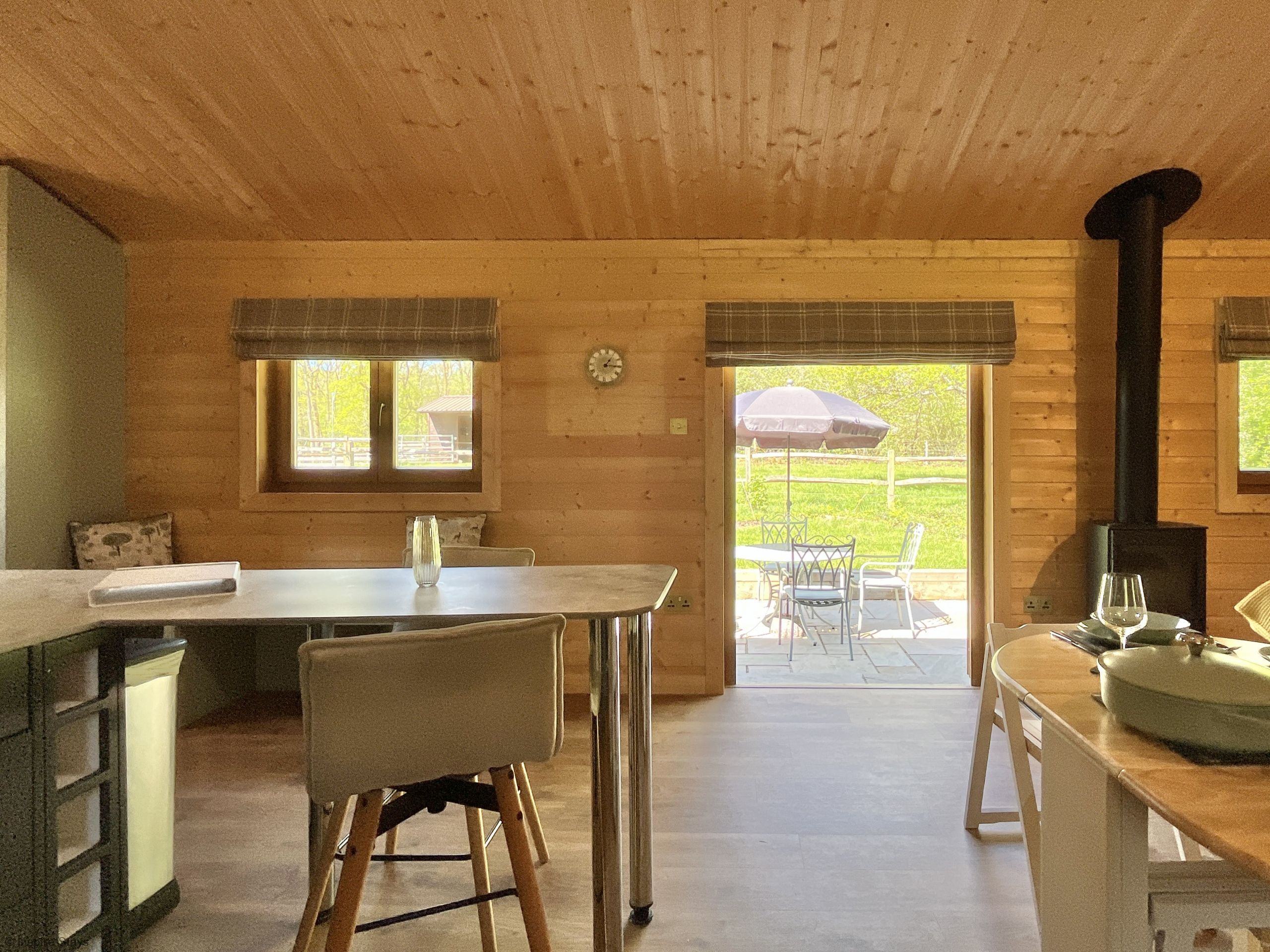 Ein Holzblockhaus-Interieur mit Esstisch, Stühlen, Küchenzeile und Kamin.