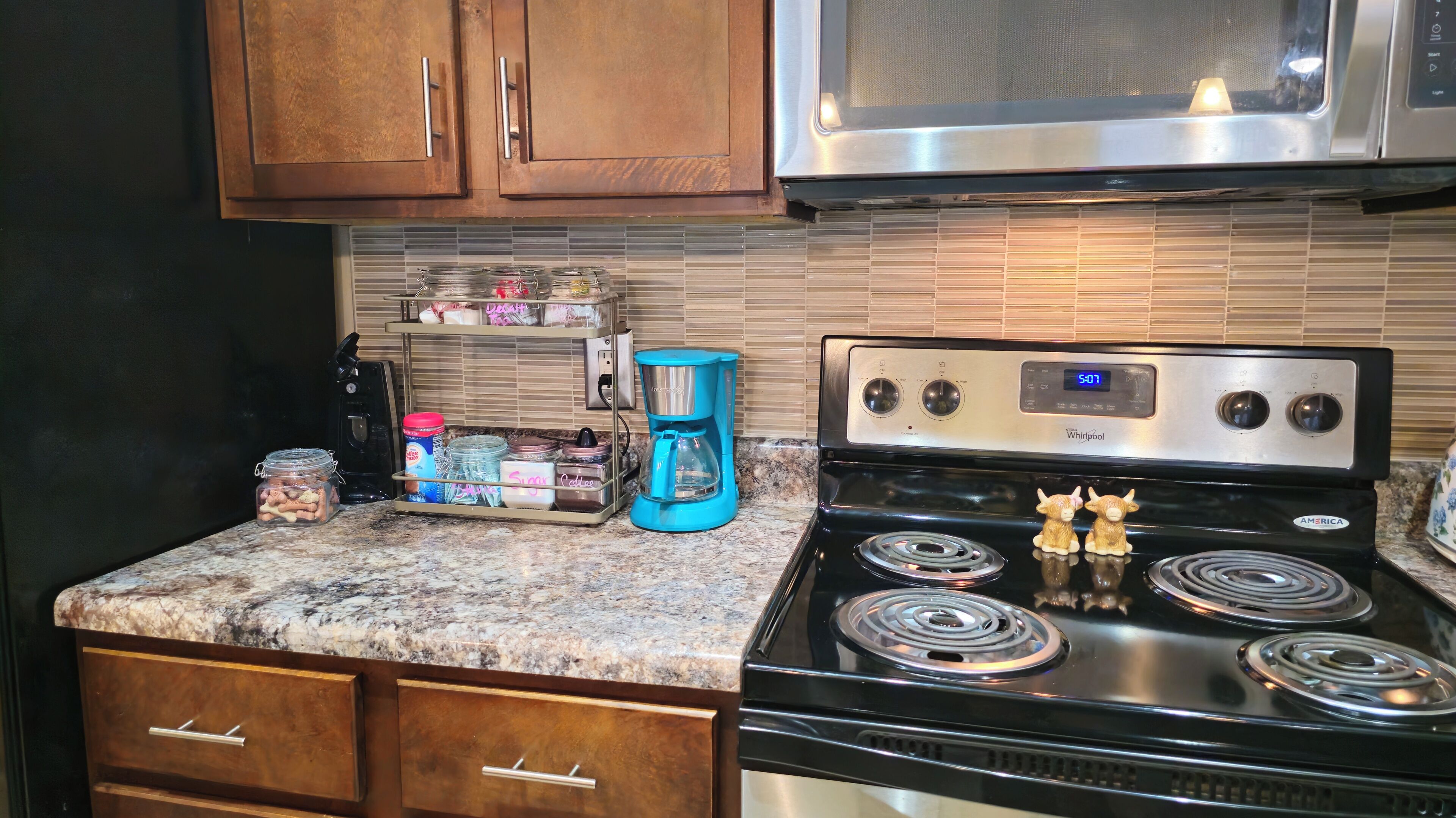 A kitchen with a stainless steel stove, a coffee maker, and wooden cabinets.