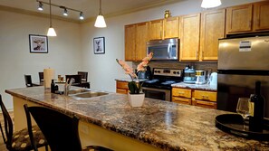 A kitchen with granite countertops, stainless steel appliances, wooden cabinets, and pendant lighting. - Mins to Mayo Clinic,Gameroom,Firepit & Beaches, king bed, Putting green (Jacksonville)