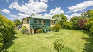 A house with a green roof, a front porch, and a well-maintained lawn.