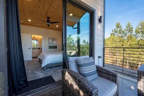 Ein Schlafzimmer mit einem Bett, einem Deckenventilator und einem großen Fenster.