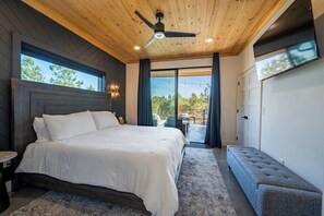 Ein Schlafzimmer mit einem großen Bett, einem Deckenventilator und Blick ins Freie.