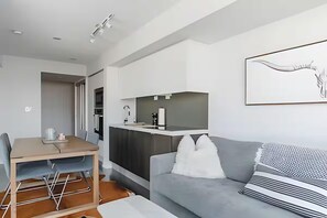 A modern living space with a dining area, kitchenette, and a grey sofa with patterned cushions. - King West Place (Toronto)