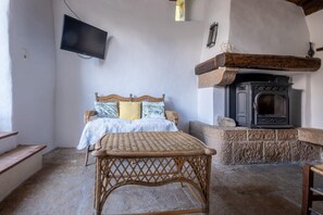 A room with a bed, a television, a fireplace, and a wicker table. - Le Barrinal - MAS-SAINT-CHELY (MAS-SAINT-CHELY)