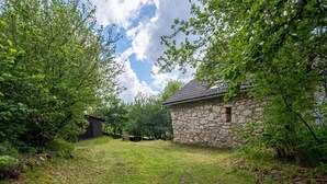 A stone building with a tiled roof, surrounded by lush greenery and trees. - Le Barrinal - MAS-SAINT-CHELY (MAS-SAINT-CHELY)