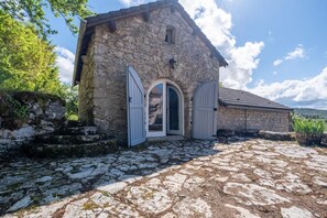 A stone building with two white doors, a stone staircase, and a paved courtyard. - Le Barrinal - MAS-SAINT-CHELY (MAS-SAINT-CHELY)