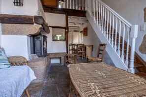 Ein rustikales Interieur mit Kamin aus Stein, Holzmöbeln und einer Treppe.