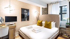 Una habitación de hotel moderna con cama, escritorio, televisor y ventana con cortinas.