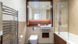 Ein modernes Badezimmer mit Duschkabine, Toilette und Waschbecken mit Spiegel darüber.