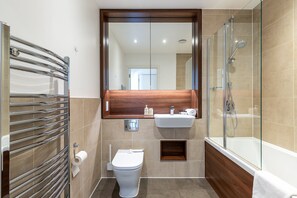 Ein modernes Badezimmer mit Duschkabine, Toilette und Waschbecken mit Spiegel darüber.