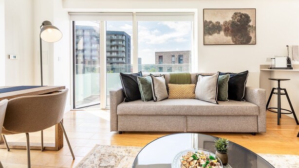 Ein modernes Wohnzimmer mit einer Couch, einem Esstisch und einem großen Fenster mit Blick auf die Stadt.
