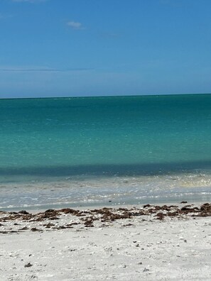 Ein Strand mit klarem türkisblauem Wasser und weißem Sand.