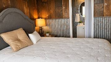 Un dormitorio con una cama grande, paredes de madera, un espejo y una mesita de noche con lámpara.